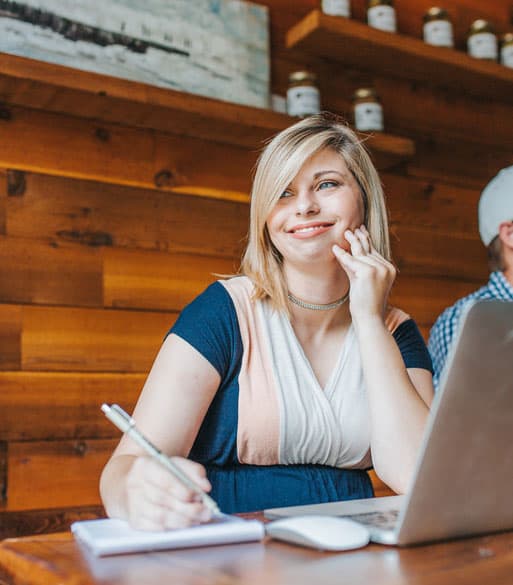Canada Tax Reviews client writing beside a laptop